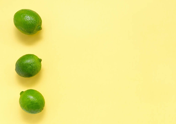 Fresh juicy limes on a yellow uniform background. Citrus Vitamin C Healthy Eating and Lifestyle - Fotó, kép