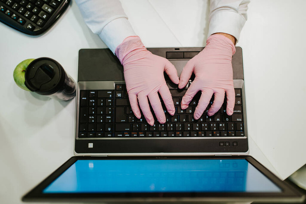 Biznesmen w rękawiczkach wpisujący na klawiaturze. COVID - 19 ochrona przed wirusami - Zdjęcie, obraz