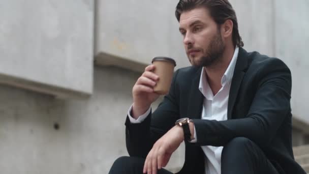 Podnikatel, který pije, si ve městě odnáší kávu. Mužský dělník sedící na schodech - Záběry, video
