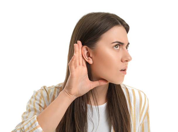 Νεαρή γυναίκα προσπαθεί να ακούσει κάτι σε λευκό φόντο - Φωτογραφία, εικόνα