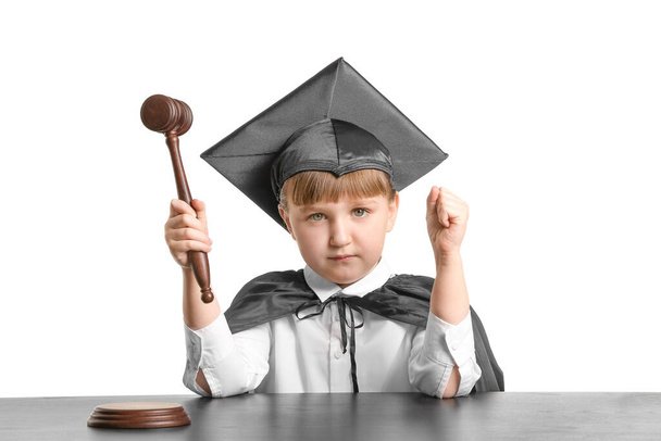 Portrait of little judge sitting at table against white background - Photo, Image