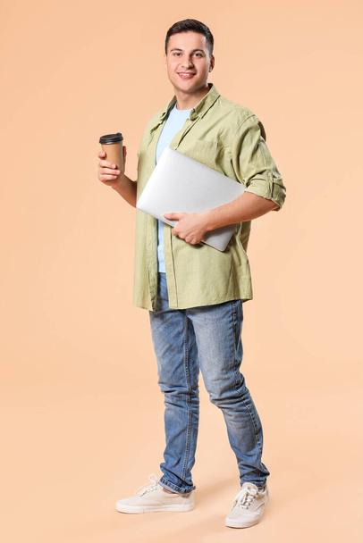 Retrato de hombre joven con portátil y café sobre fondo de color
 - Foto, Imagen