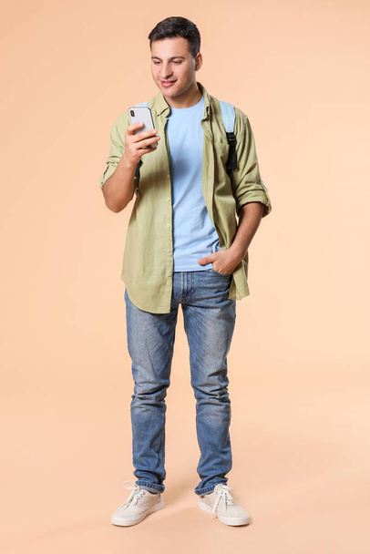 Portrét studenta s mobilním telefonem na barevném pozadí - Fotografie, Obrázek