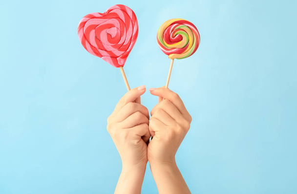 Hands with sweet lollipops on color background - Photo, Image