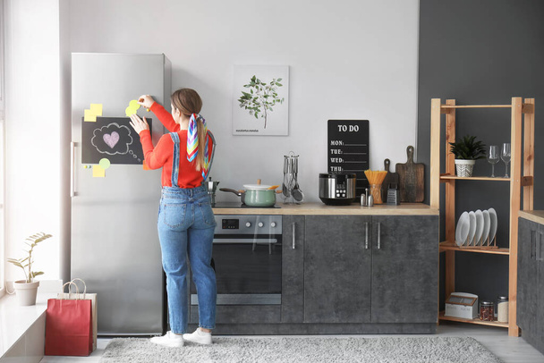 Young woman near refrigerator in kitchen - Photo, Image