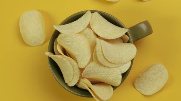 Kartoffelchips in einer Keramikschüssel auf gelbem Hintergrund. Ansicht von oben. - Filmmaterial, Video