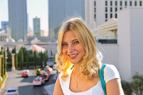 Smiling blonde girl in a summer town - 写真・画像