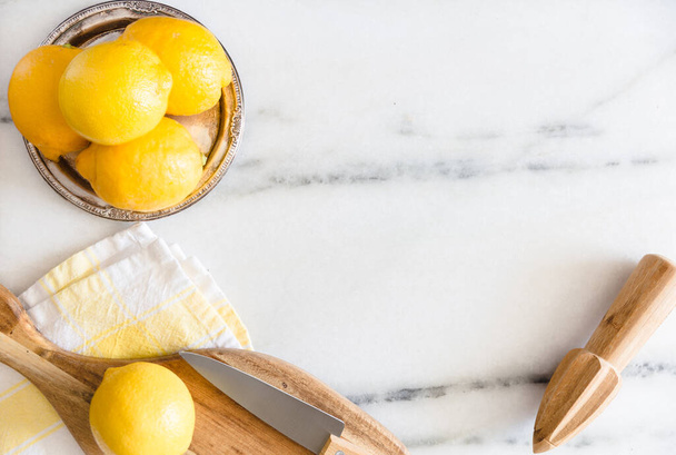Frische Zitronen mit Küchenutensilien auf einer Marmoroberfläche. - Foto, Bild