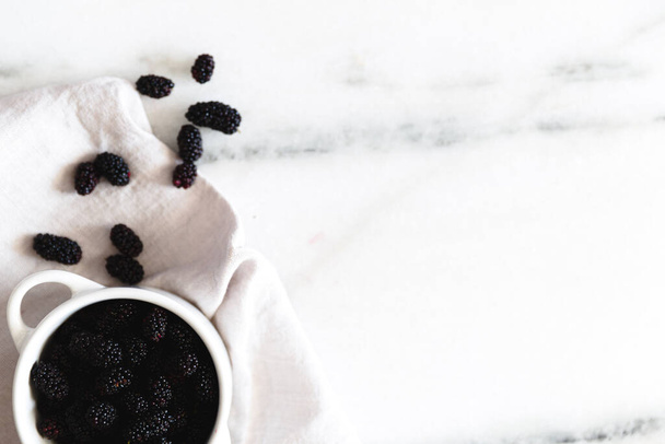 Blackberries on a white marble surface. - Foto, afbeelding