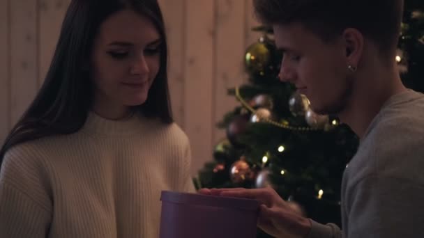 Una giovane coppia, un uomo e una donna a casa aprono una confezione regalo. Sono sorpresi e si rallegrano
. - Filmati, video