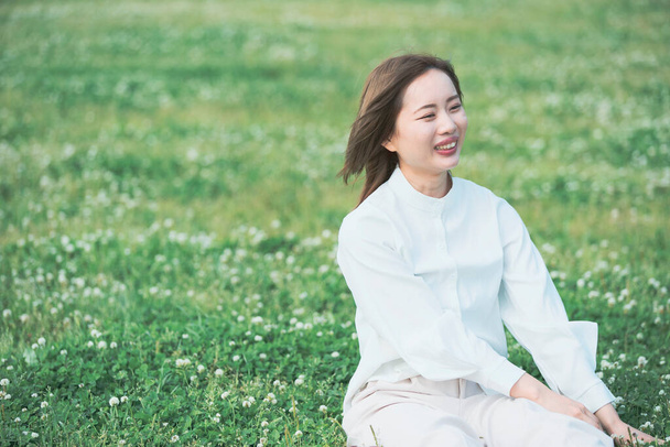 Mujer joven asiática mostrando una expresión relajada en el prado
 - Foto, imagen