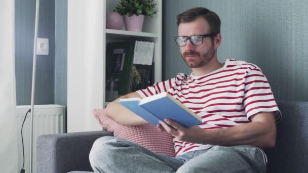 biały młody dobrze wygląda człowiek w okularach czyta książkę - Materiał filmowy, wideo