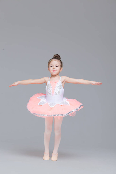 Cute adorable ballerina little girl in pink tutu dance practices ballet dancing - Foto, Imagen