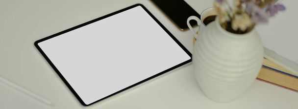 Boş ekran tableti, akıllı telefon ve beyaz masanın üzerindeki dekorasyonla en az çalışma alanı görüntüsü.   - Fotoğraf, Görsel