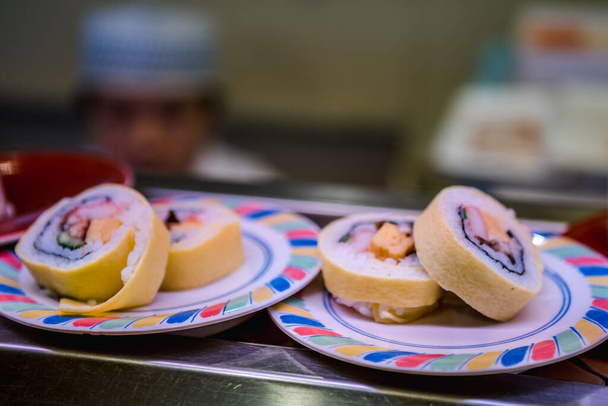 Sushi na pásovém dopravníku v japonské restauraci. Tradiční Kaitenzushi japonské jídlo. Shushi Go Round je slavná forma fast foodů v Asii, také známý jako sushi vlak. - Fotografie, Obrázek