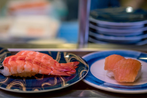 Japonya 'da bir restoranda taşıma bandında suşi. Geleneksel Kaitenzushi Japon yemekleri. Shushi Go Round, Asya 'da suşi treni olarak da bilinen ünlü bir fast food türüdür.. - Fotoğraf, Görsel