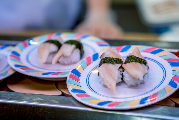 Sushi auf dem Band in einem japanischen Restaurant. Traditionelles japanisches Kaitenzushi-Essen. Shushi Go Round ist eine berühmte Form von Fast Food in Asien, auch als Sushi-Zug bekannt. - Foto, Bild