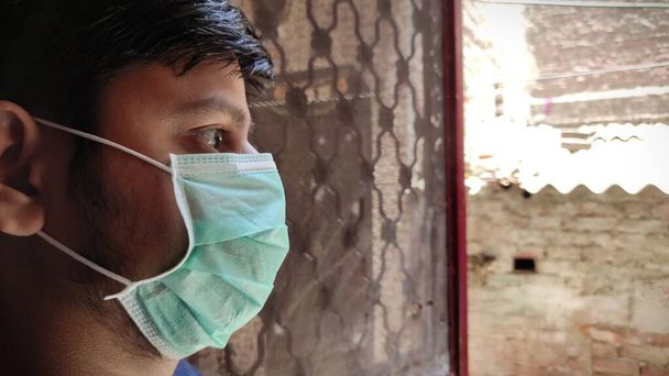 Man wearing mask looking outside open door ,Home quarantine, feeling bored,Covid 19, corona virus pandemic. - Photo, Image
