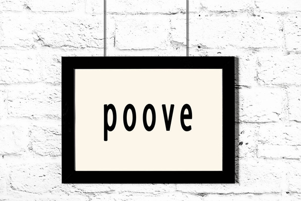 Черная рамка висит на стене из белого кирпича с надписью "poove"
 - Фото, изображение