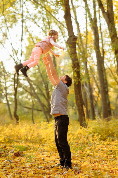 Отец и дочь веселятся вместе. Отец бросает свою дочь в небо
. - Фото, изображение