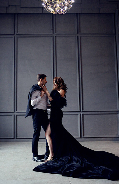a beautiful rich girl in a luxurious black velvet dress and an elegant man in a suit in an expensive interior - 写真・画像