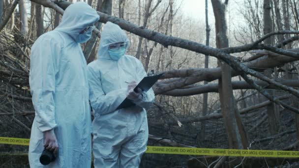 Forensic specialist working in the forest. Police criminalists collecting evidence and making criminal investigation. Crime scene concept. - Video, Çekim