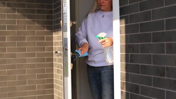 Mladá dívka dezinfikuje kliku dveří - Záběry, video