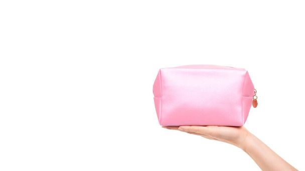 Hand with pink makeup bag. Glamour cosmetic accessory. Isolated on white background. Copy space, template. - Fotó, kép