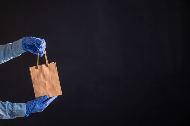 Express home delivery in the epidemic of coronavirus. Courier in gloves with a paper bag. Packaging made from eco friendly recycled material. Buying products online in quarantine. - Fotoğraf, Görsel