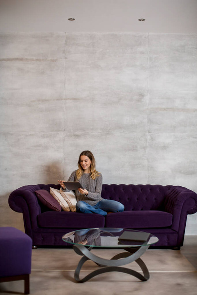 Pretty young woman with digital tablet on the sofa - Photo, Image