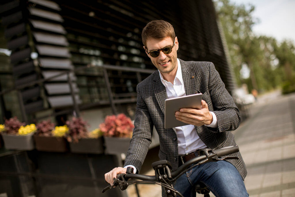 Handosme Jungunternehmer auf dem E-Bike mit digitalem Tablet - Foto, Bild
