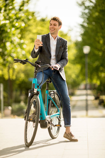 Молодий бізнесмен на велосипеді робить селфі фотографію за допомогою мобільного телефону. - Фото, зображення