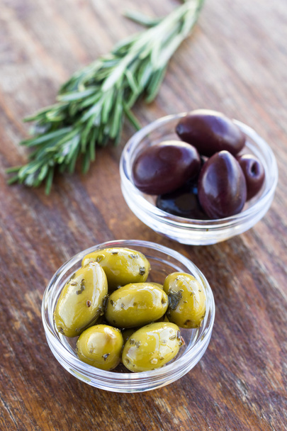 Teller mit grünen und schwarzen Oliven auf Holzoberfläche - Foto, Bild