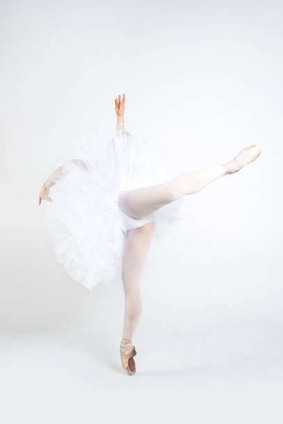Молодая балерина, практикующая балетные движения в студии
 - Фото, изображение