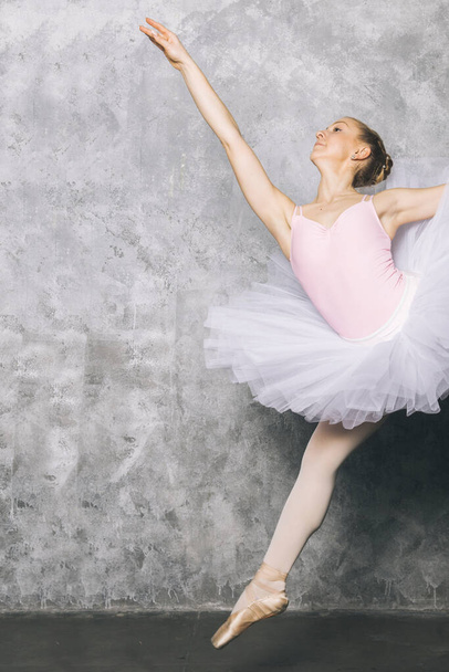 Pretty young ballerina dancer dancing classical ballet against old rustic wall - Photo, Image