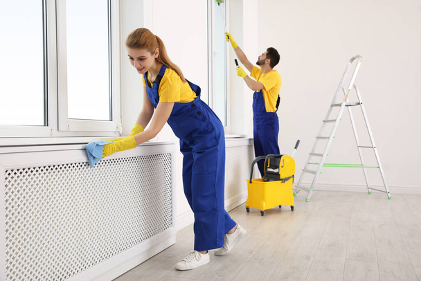 Professional janitors in uniform cleaning spacious room - 写真・画像