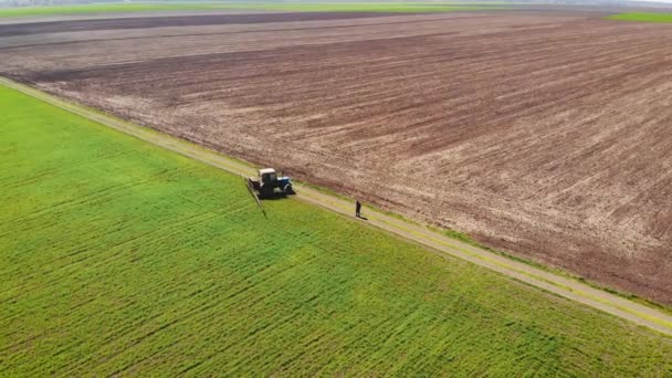 Tiro aéreo de dron del agricultor en tractor con pulverizador montado con productos químicos en el interior gira en el borde del campo con cebada o trigo
 - Imágenes, Vídeo