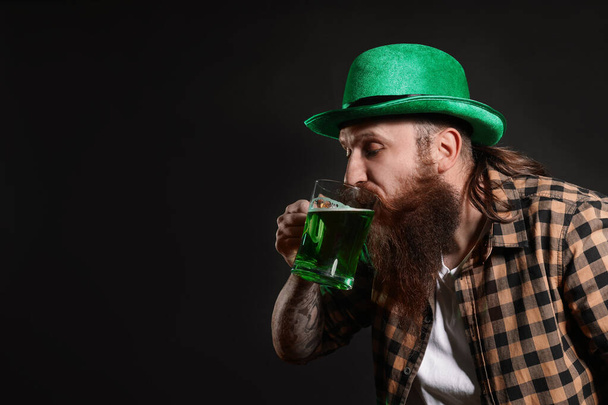 Bearded man drinking green beer on black background, space for text. St. Patrick's Day celebration - Foto, Bild
