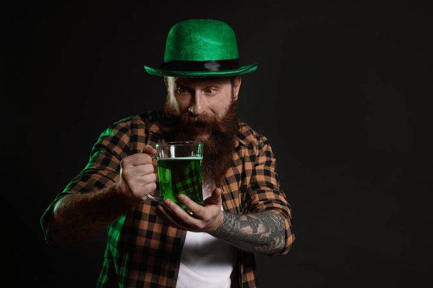 Bearded man with green beer on black background. St. Patrick's Day celebration - Photo, Image