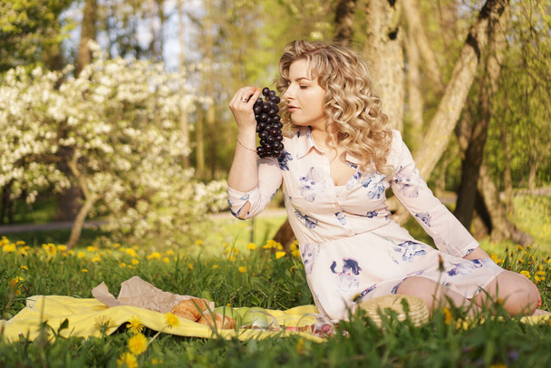 Woman with grape at a picnic in summer garden - Photo, Image