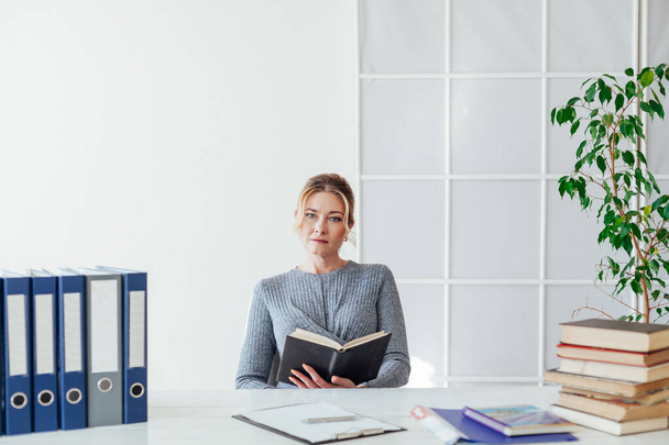beautiful business woman sits at desk with teachers books - Photo, Image