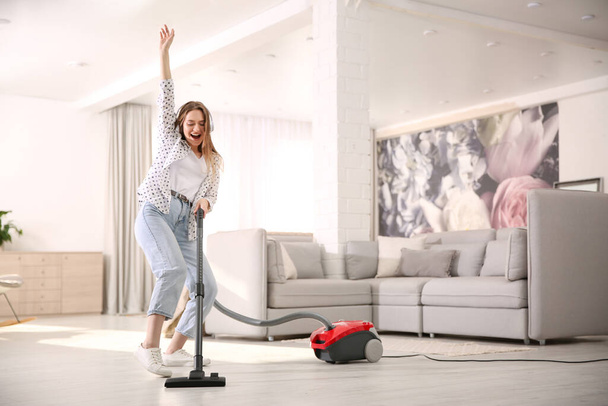Young woman having fun while vacuuming at home - Foto, Imagem