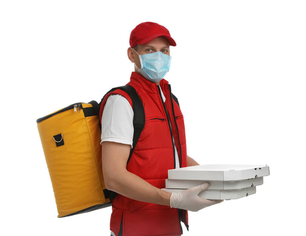 Courier in protective mask and gloves holding pizza boxes on white background. Food delivery service during coronavirus quarantine - Foto, imagen