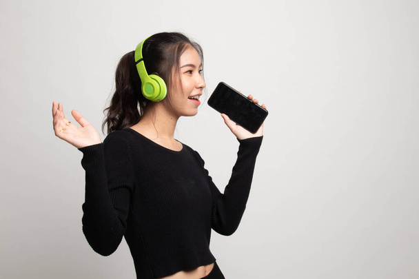 Pretty asian girl listening music with her headphones on white background - Фото, зображення