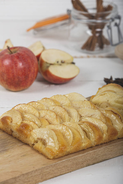 Primer plano del pequeño pastel de manzana con masa de brioche en la tabla de cortar de madera con varios ingredientes. imagen vertical
 - Foto, imagen