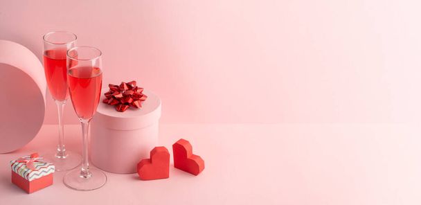 Round gift boxes, red hearts and glasses of sparkling wine on pink background - Valokuva, kuva