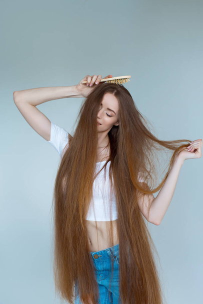 Fogalom a hajhullásról. Közelkép portré boldogtalan szomorú stresszes fiatal nő hosszú, száraz barna haj, elszigetelt szürke háttér. - Fotó, kép