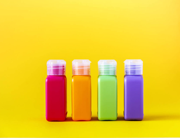 Colorful plastic bottles for skincare products on bright yellow background - Foto, Bild