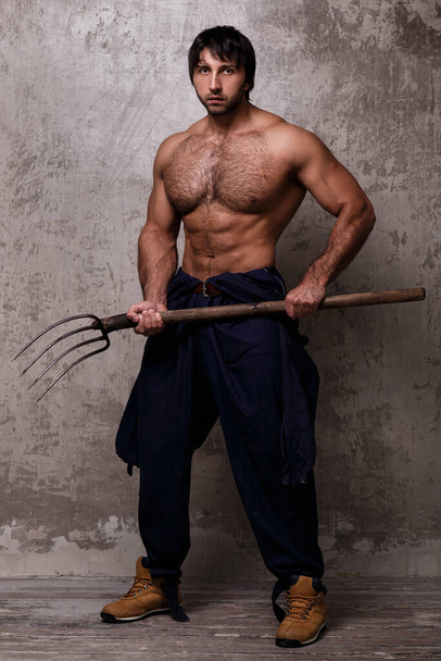 Guy with perfect body holding pitchfork - Фото, зображення