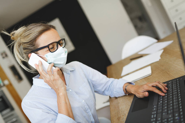 krásná žena s lékařskou maskou pracuje s notebookem doma kancelář - Fotografie, Obrázek